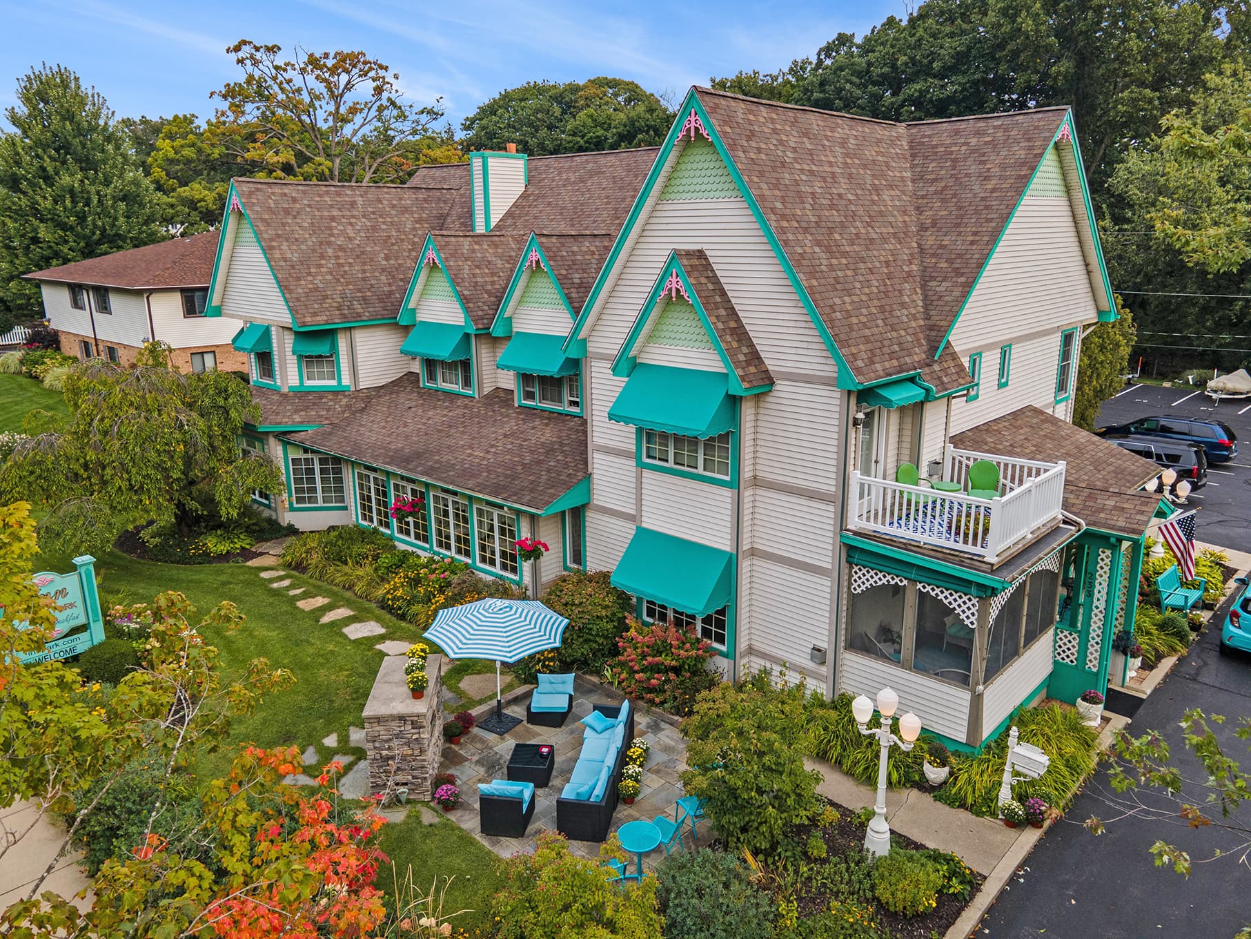 A charming multi-story house with teal accents surrounded by lush greenery and a well-kept garden. A charming multi-story house with teal accents surrounded by lush greenery and a well-kept garden.