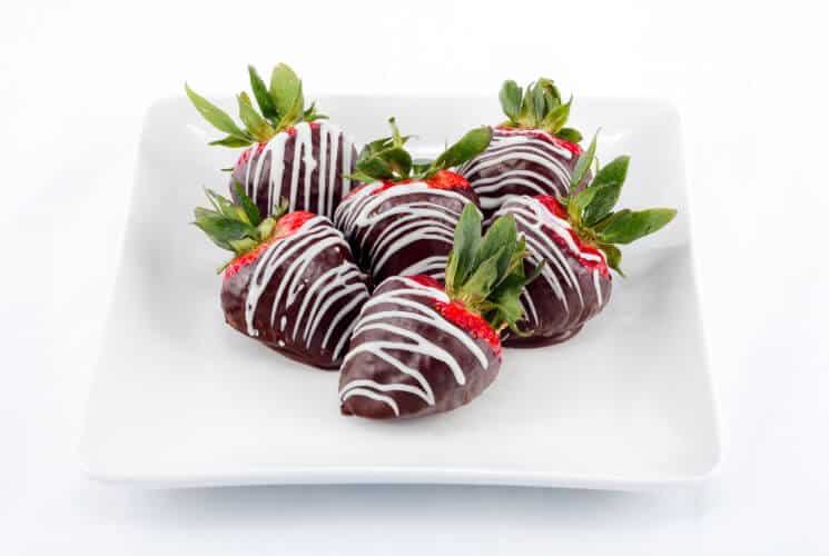 A plate of chocolate-covered strawberries drizzled with white chocolate.