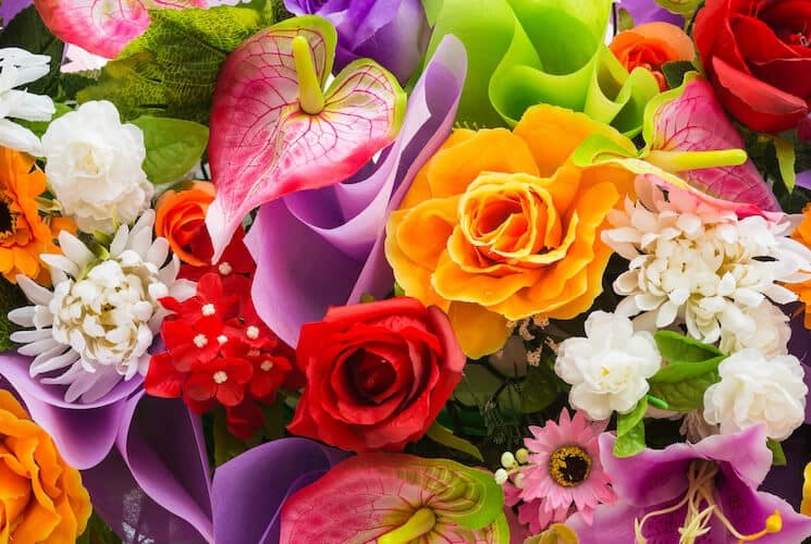 A vibrant bouquet featuring a variety of colorful flowers including roses, orchids, and daisies.