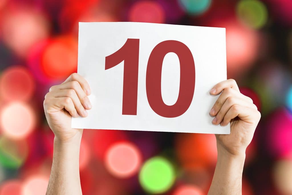 A pair of hands holding a sign with the number "10" against a blurred colorful background. A pair of hands holding a sign with the number "10" against a blurred colorful background.